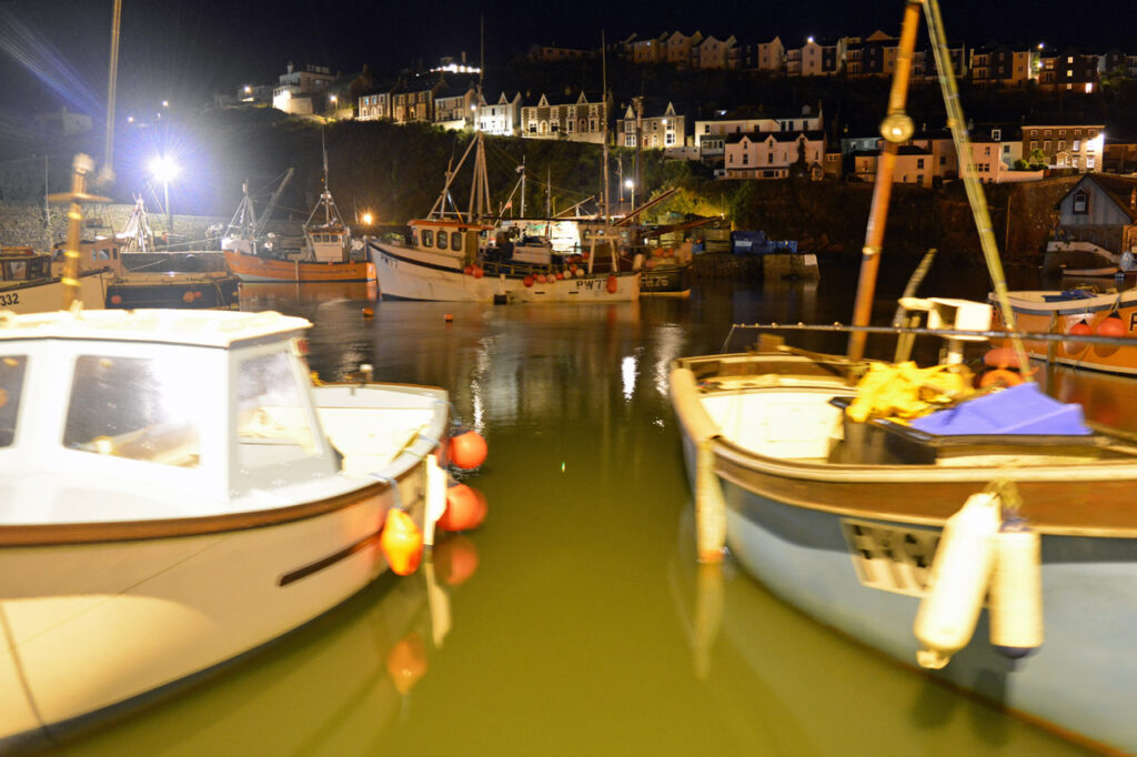 Night fishing between boats for mullet in a harbour with float & starlight